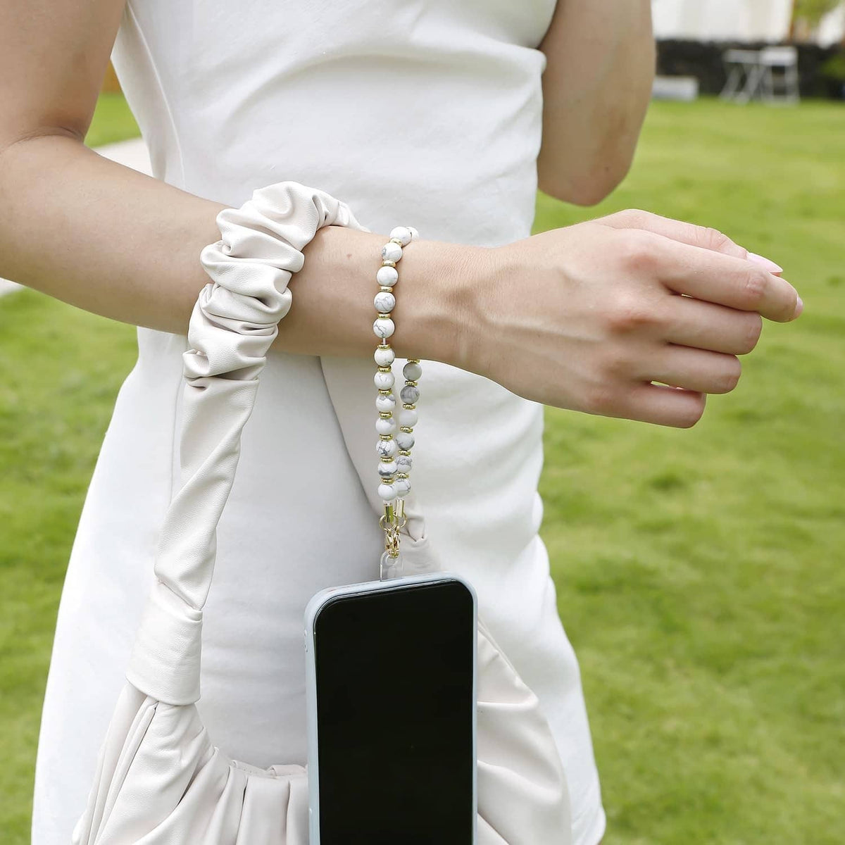 Marble white beaded wrist strap with gold chain, worn with phone
