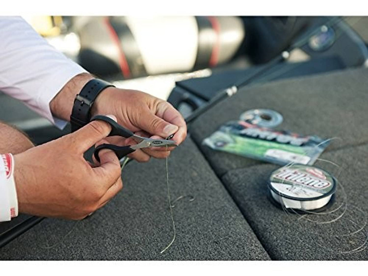 Hands tying monofilament fishing line outdoors; line spool nearby