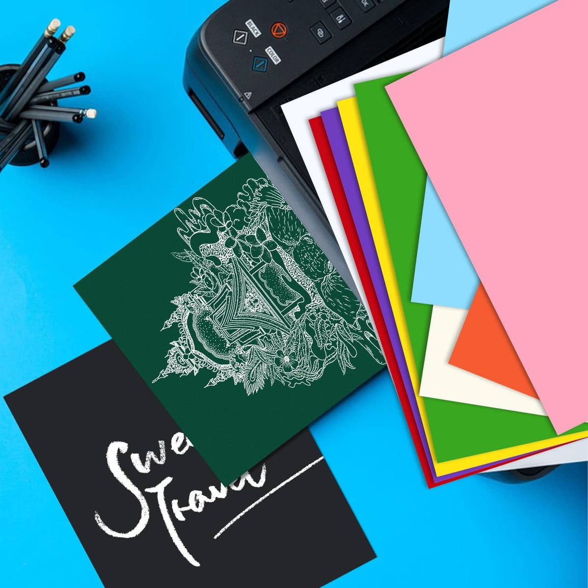 Cardstock sheets in multiple colors beside printer, including yellow