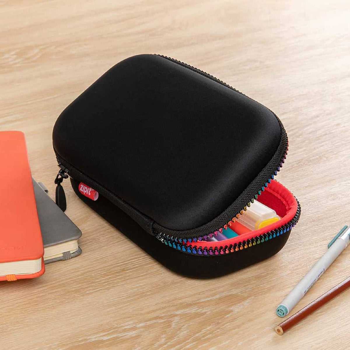 Black EVA pencil case with rainbow zipper, open showing supplies and red interior.