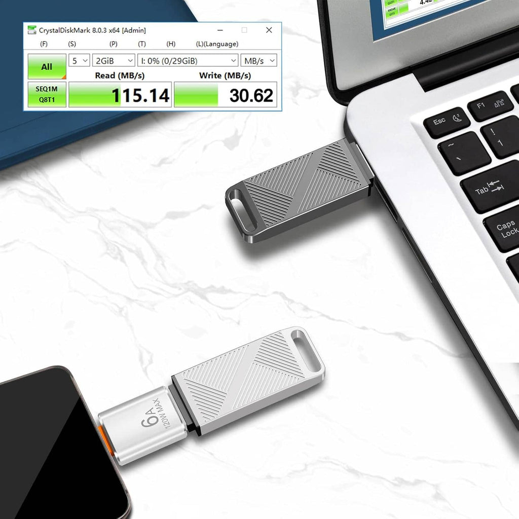 Grey USB flash drive with USB-C adapter connected near a laptop keyboard