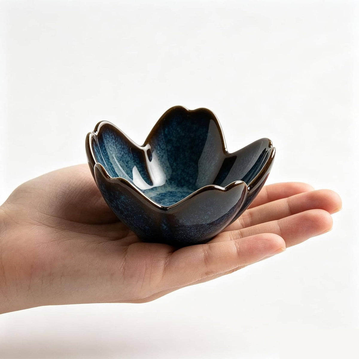 Ceramic flower ring holder dish in dark blue held in a hand