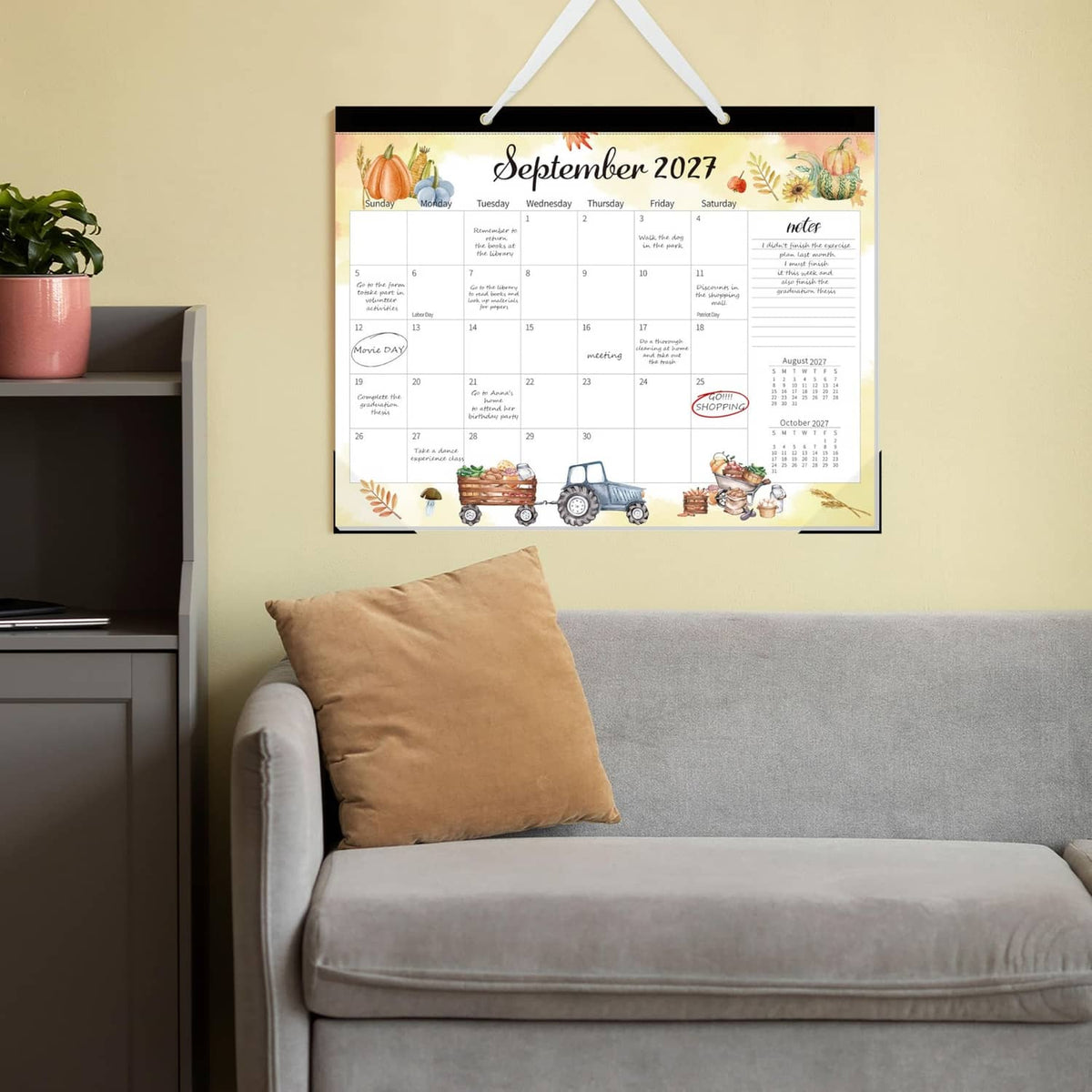 September 2027 desk calendar hanging on a wall with decorative border and grid layout