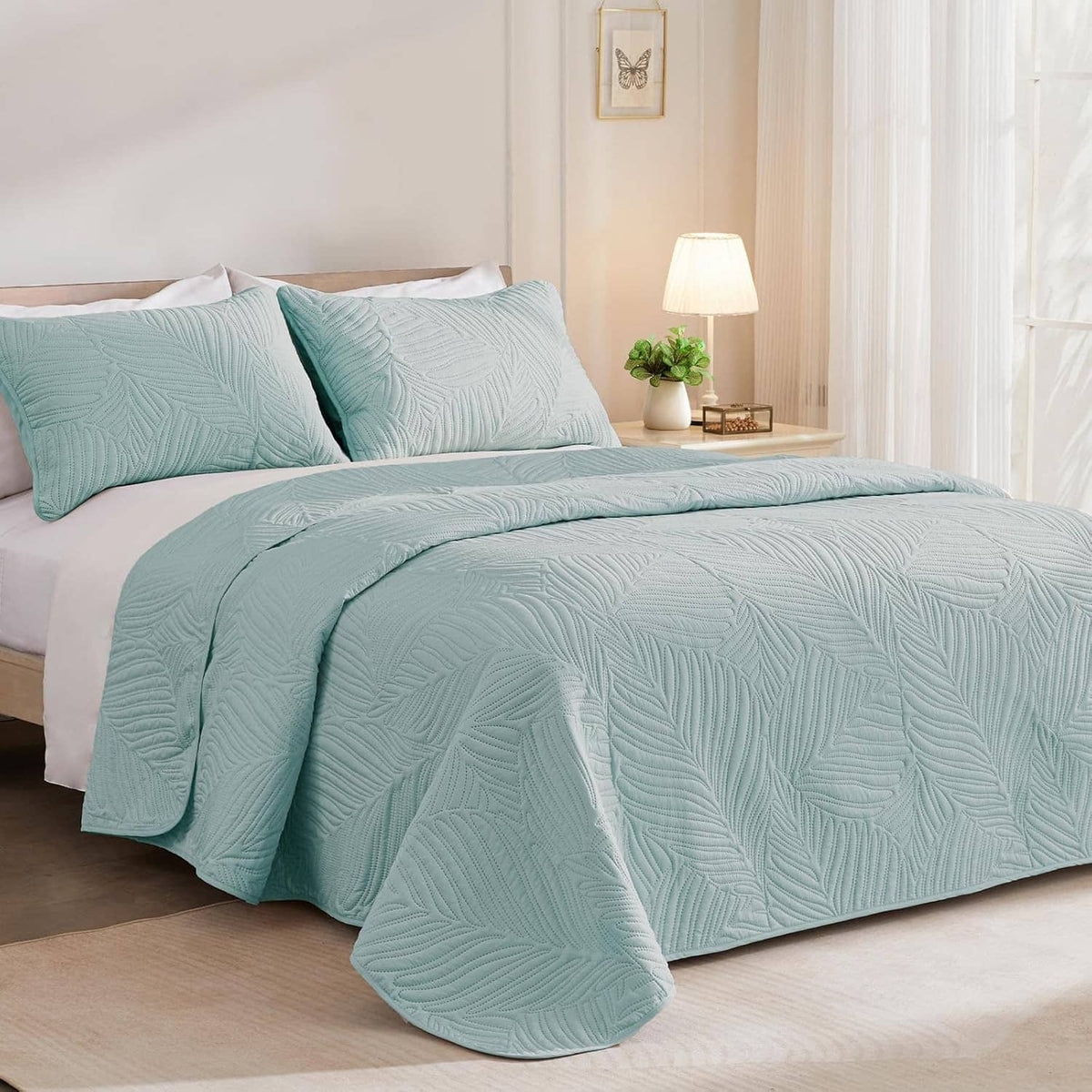 Aqua blue quilt set with leaf-pattern embossed texture and draped quilt over the bed