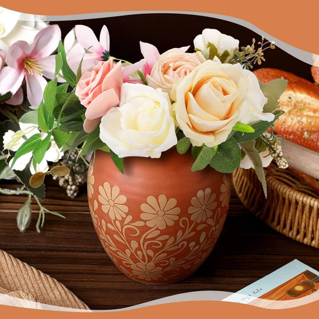 Brown Mexican clay cantarito vase with white flower pattern holding cream and pink roses