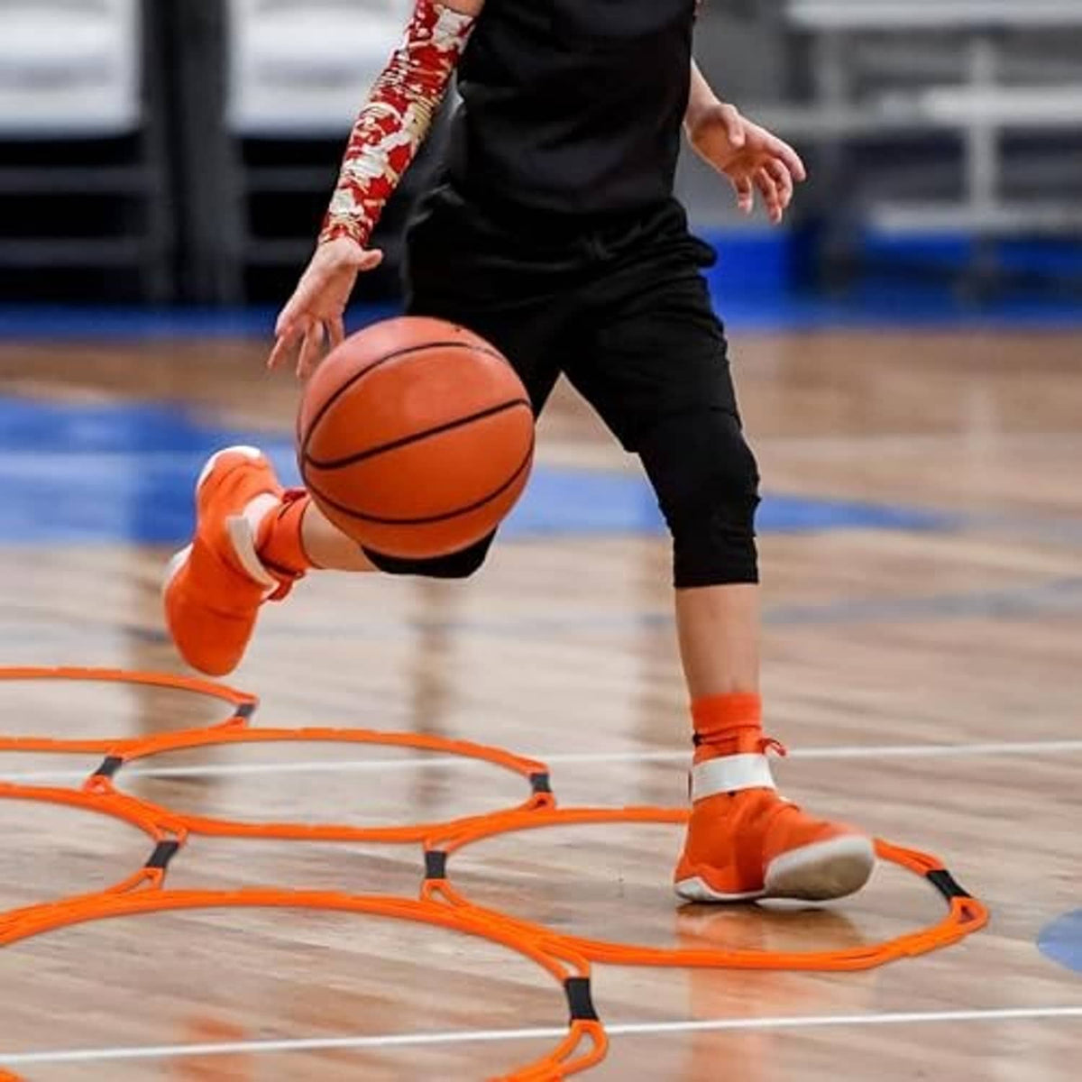Orange octagonal agility rings with black connectors on an indoor court surface.