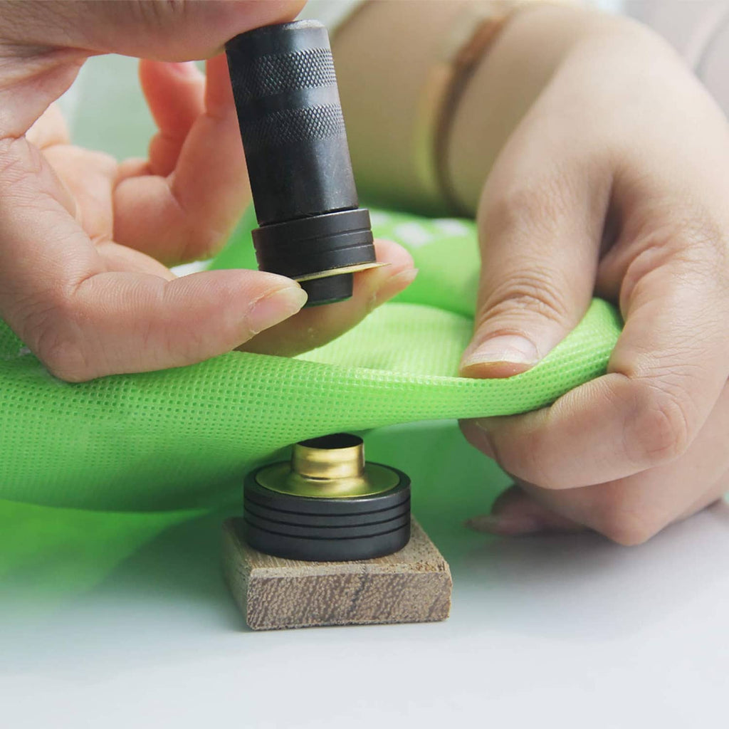 Solid brass grommet installation using a punch tool on fabric and a wooden block anvil