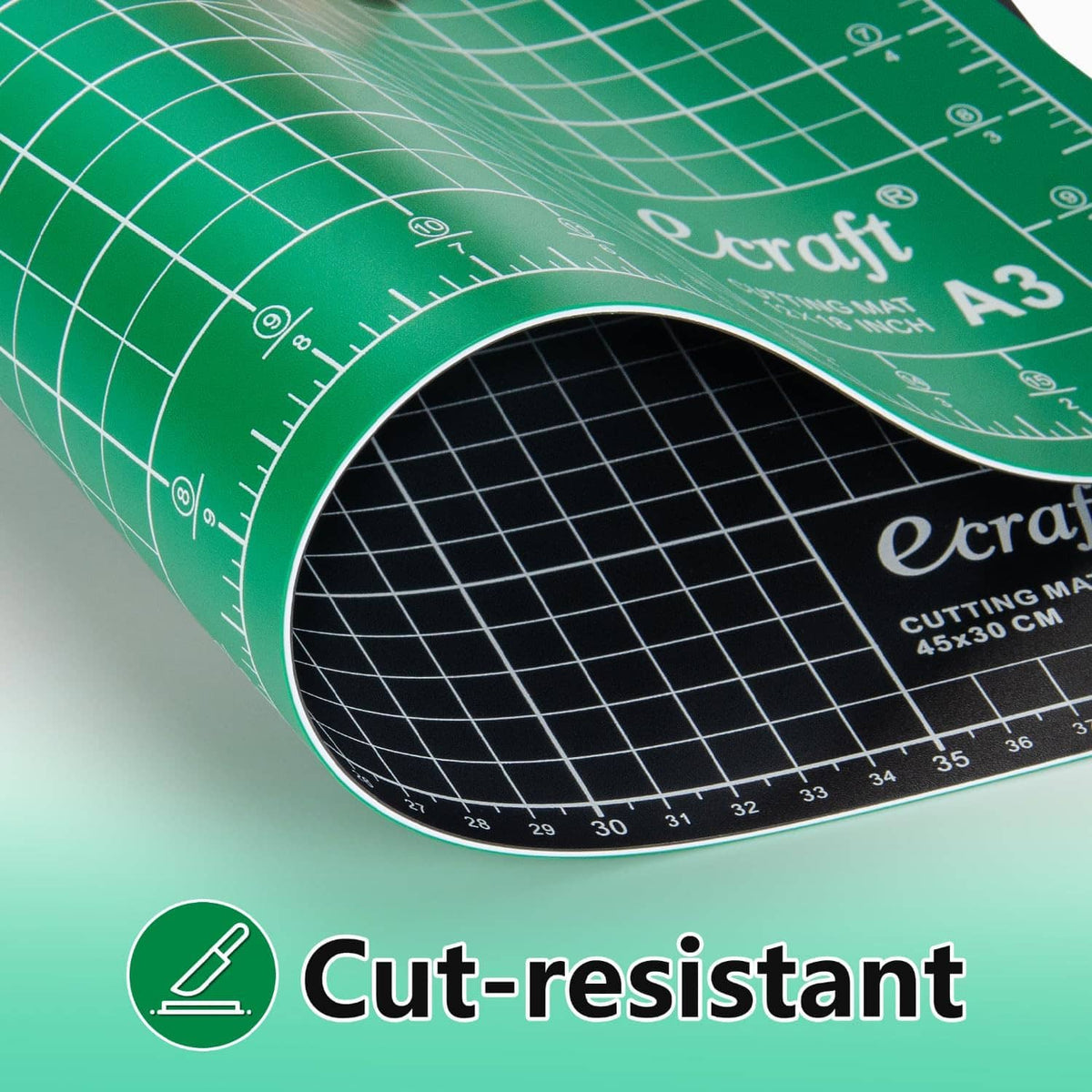 Close-up of green cutting mat edge showing grid markings and black underside