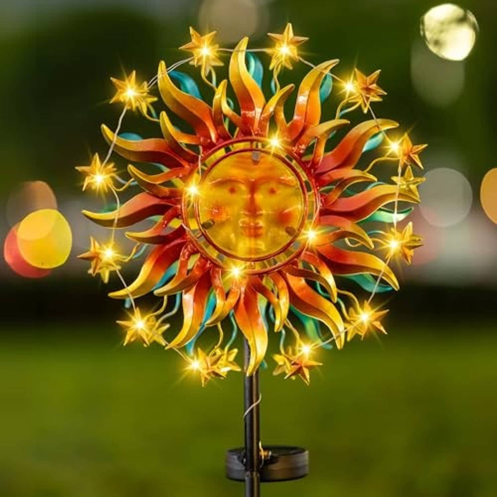 Solar metal sun wind spinner with colorful rays and bright warm light on yard pole.