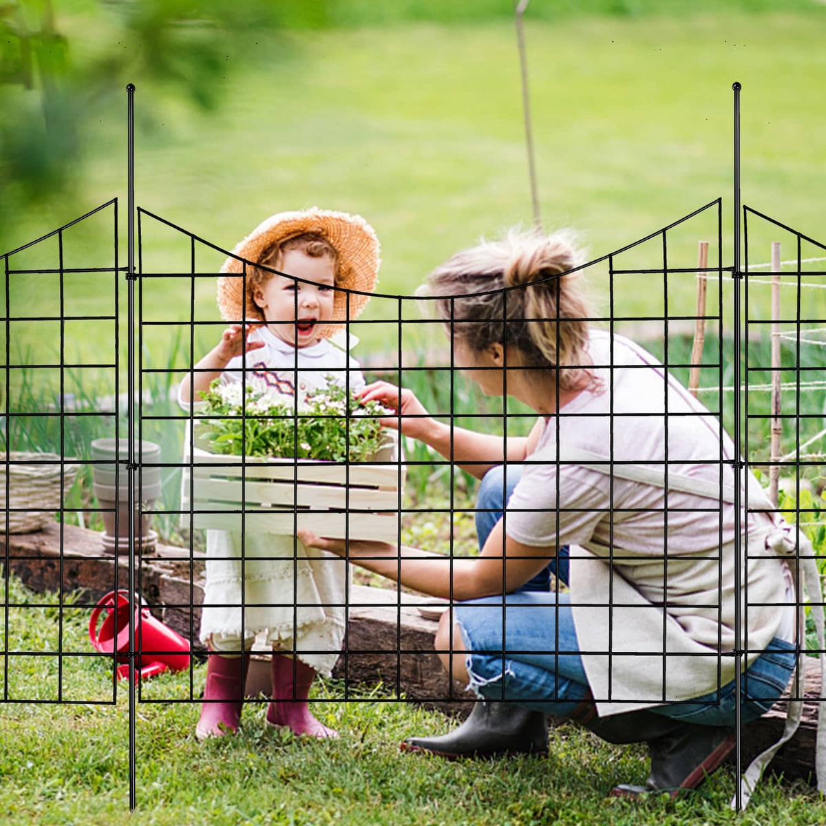 Black metal garden fence grid with stakes enclosing kids and dog in yard
