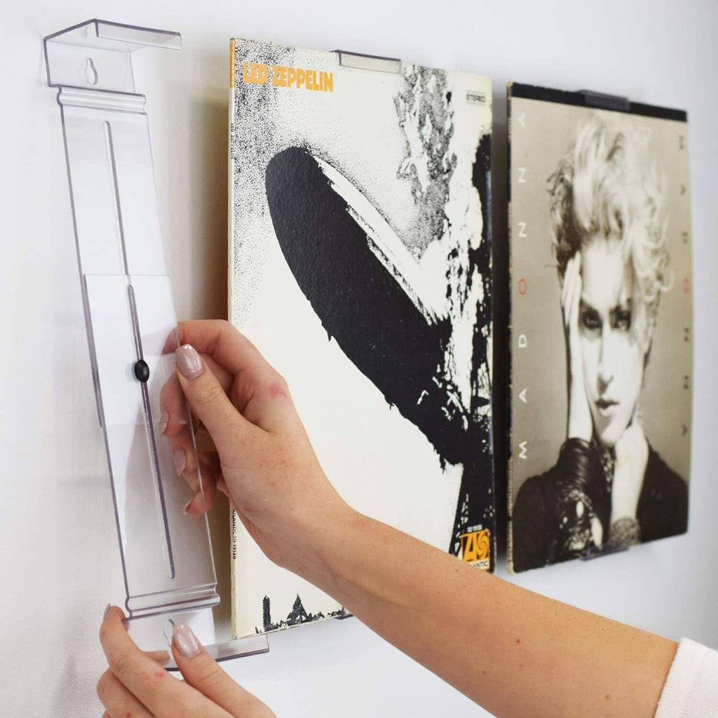 Hand loading an album cover into a clear wall-mount display bracket