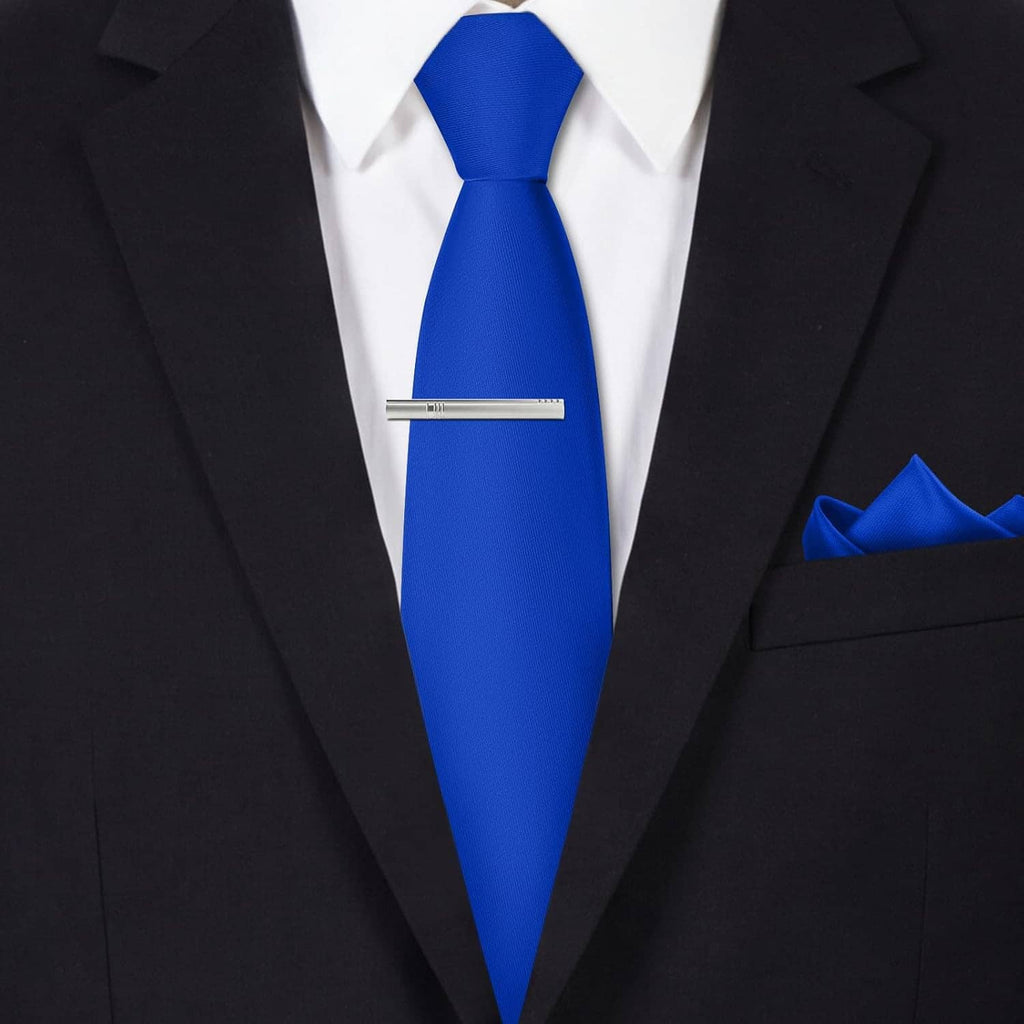 Men's blue tie set with tie clip and folded pocket square, worn with suit jacket