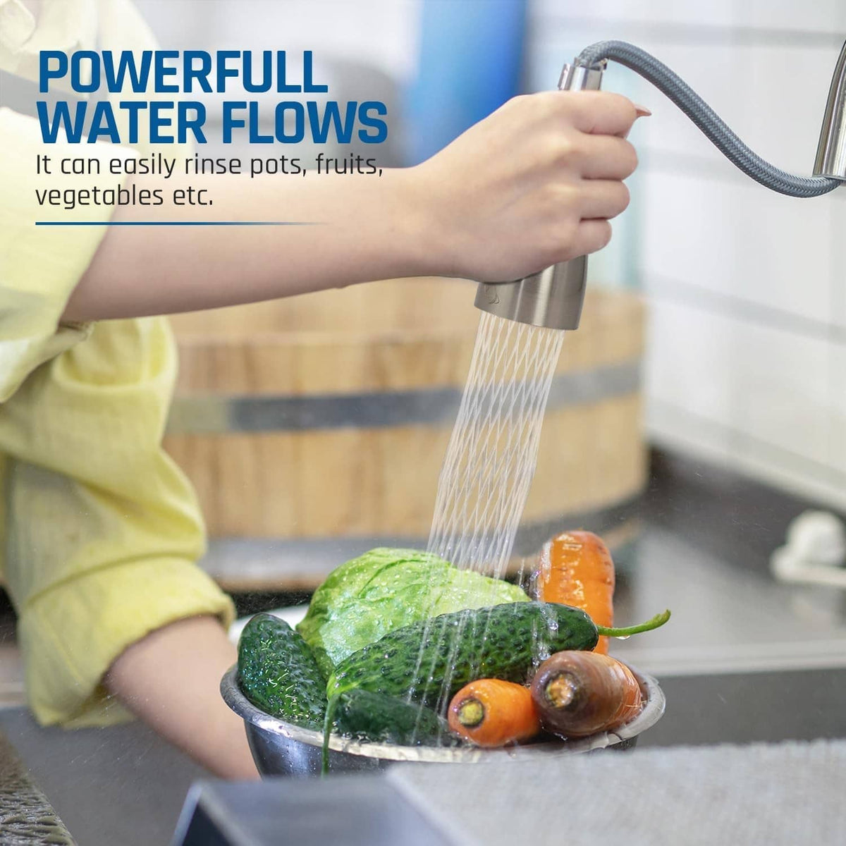 Hand rinsing vegetables with brushed nickel pull-down faucet head sprayer water stream