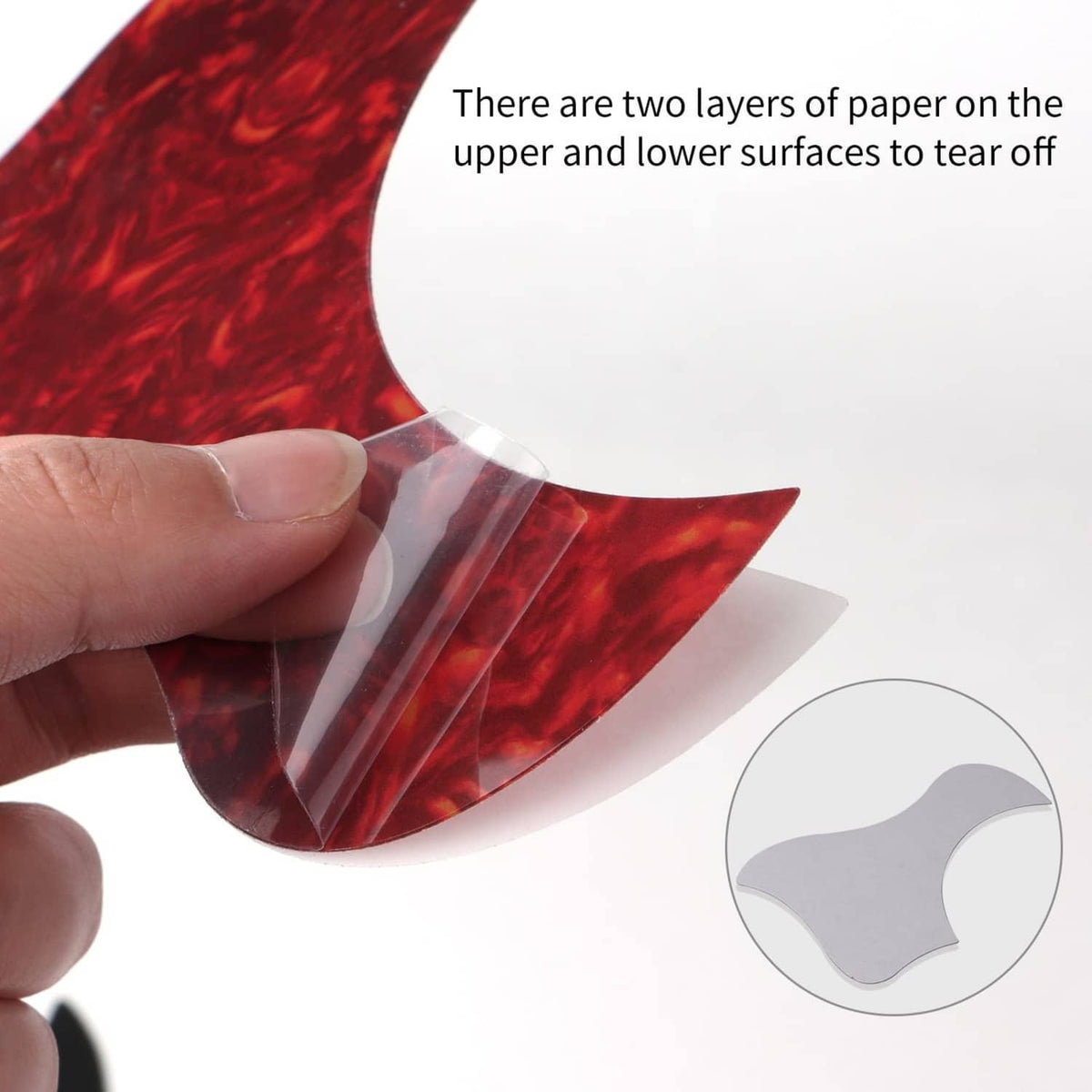 Hand applying a self-adhesive red acoustic guitar pickguard with clear backing
