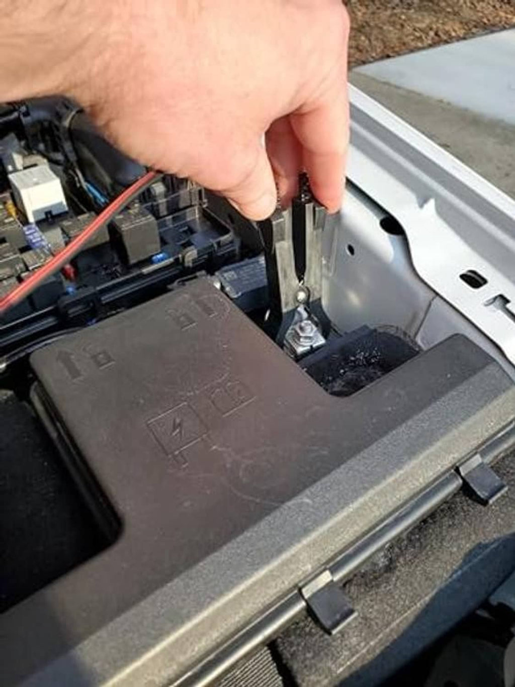 Hand using relay puller to lift an automotive relay from a fuse panel socket.
