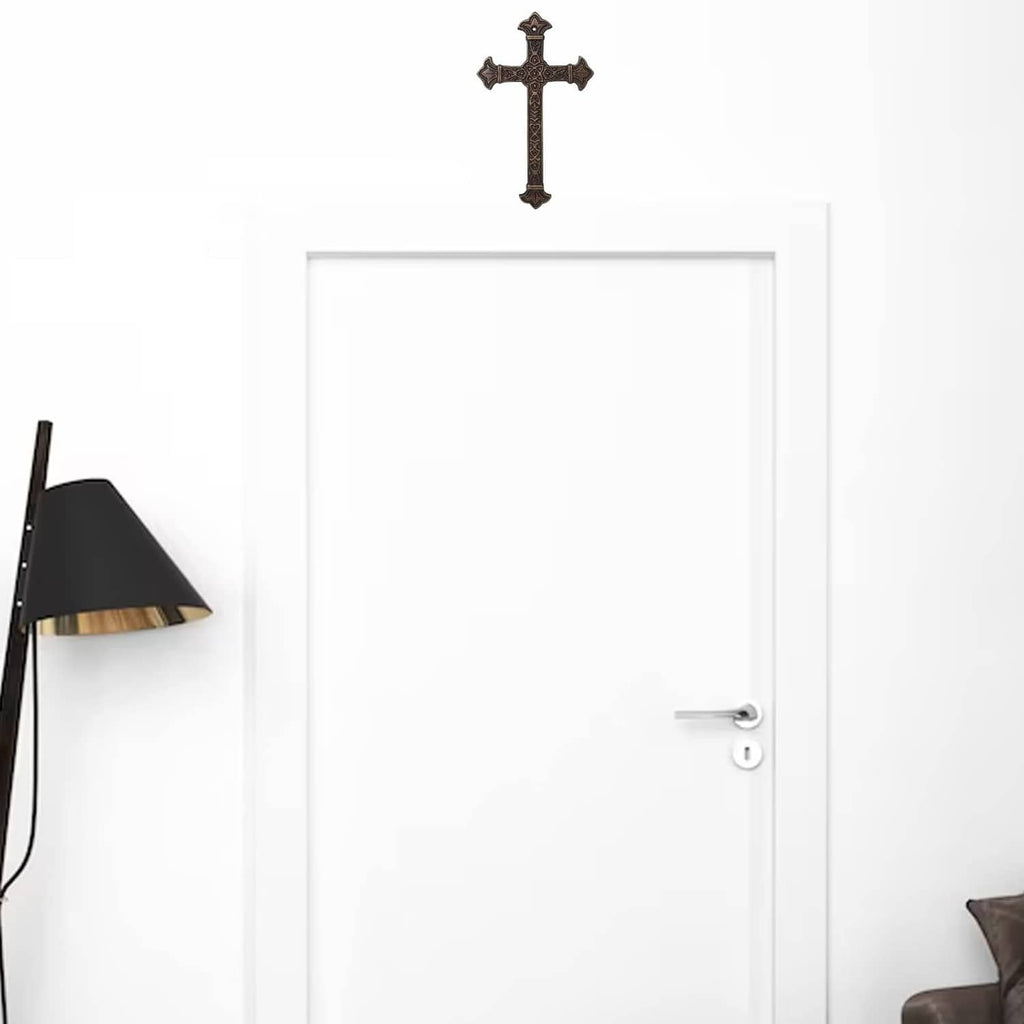 Small antique metal wall cross with raised detailing above a doorway