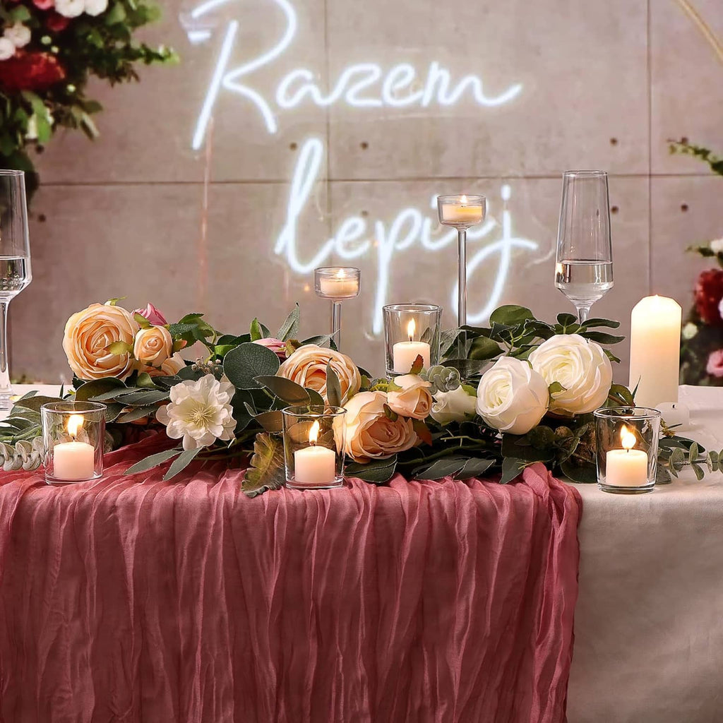 Clear glass votive holders with lit tea lights on a floral table centerpiece