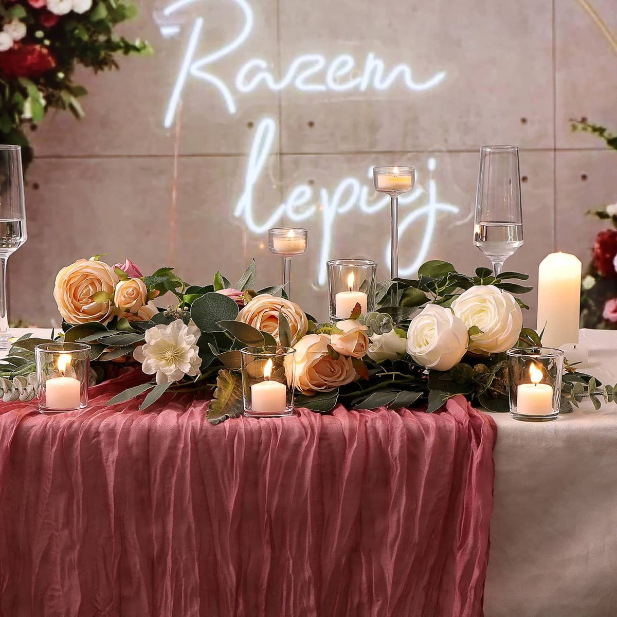 Clear glass votive holders with lit tea lights on a floral table centerpiece