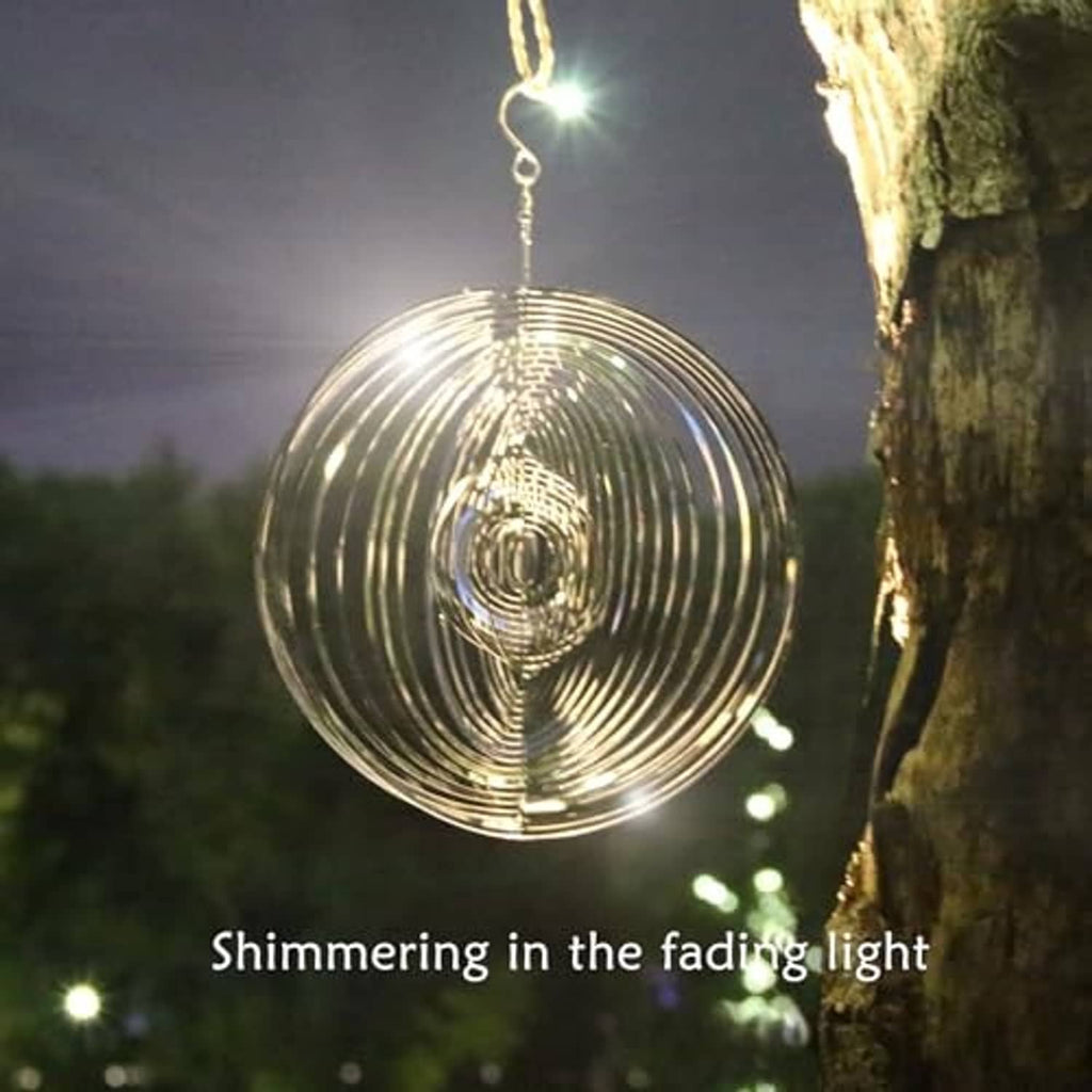 Silver round wind spinner with concentric metal rings hanging outdoors