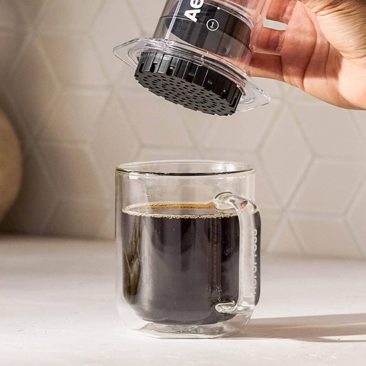 AeroPress brewing chamber with used coffee filter disc and mug