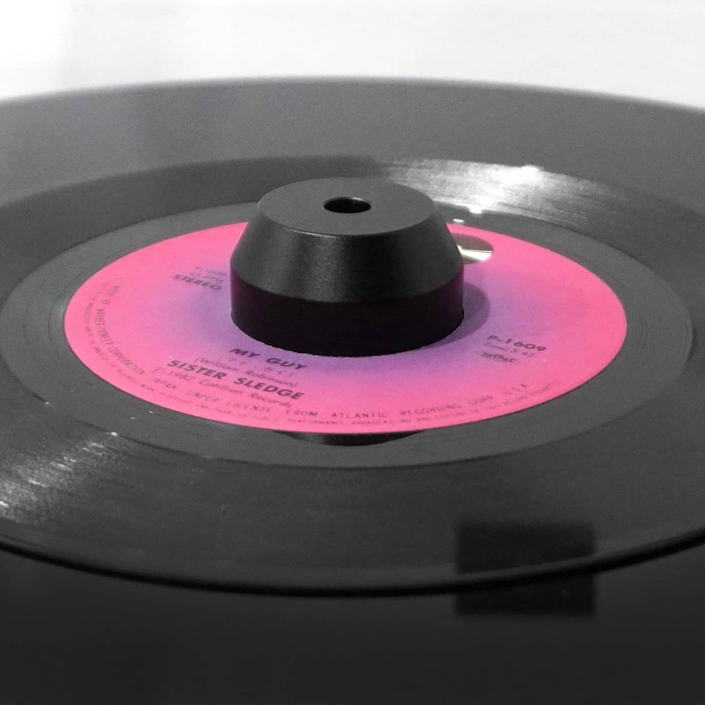 Black 45 RPM center adapter seated on a vinyl record center spindle hole