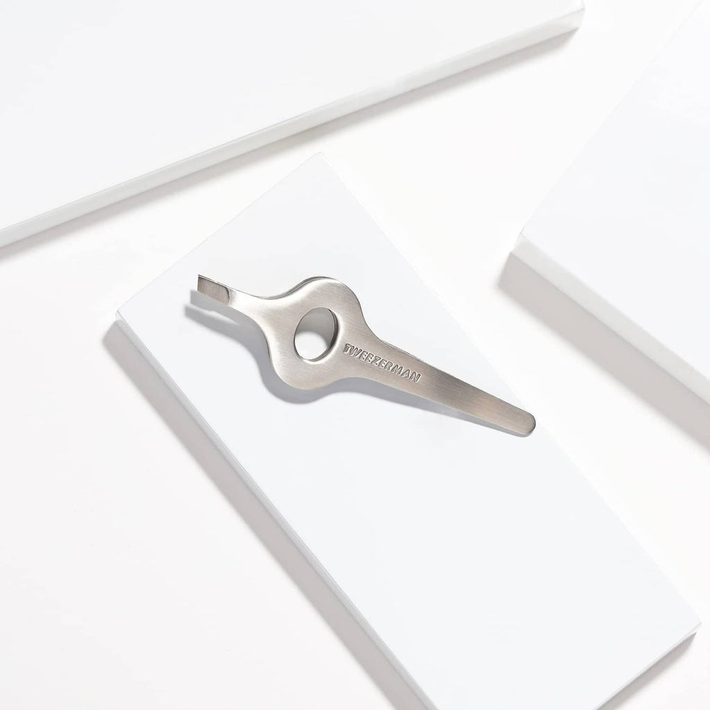 Silver wide grip slant tweezer resting on white box