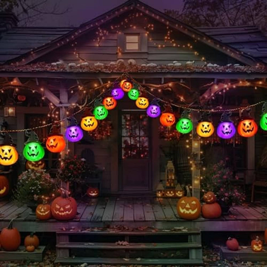 Outdoor solar pumpkin string lights with multicolor glowing jack-o'-lantern bulbs across a house porch.
