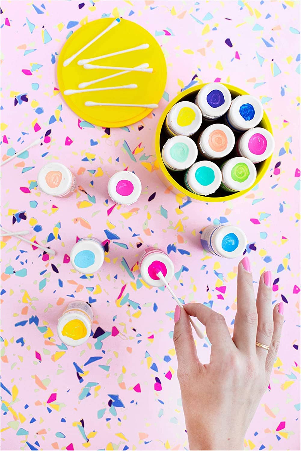 Hands using a cotton swab for colorful paint swatches inside open palettes