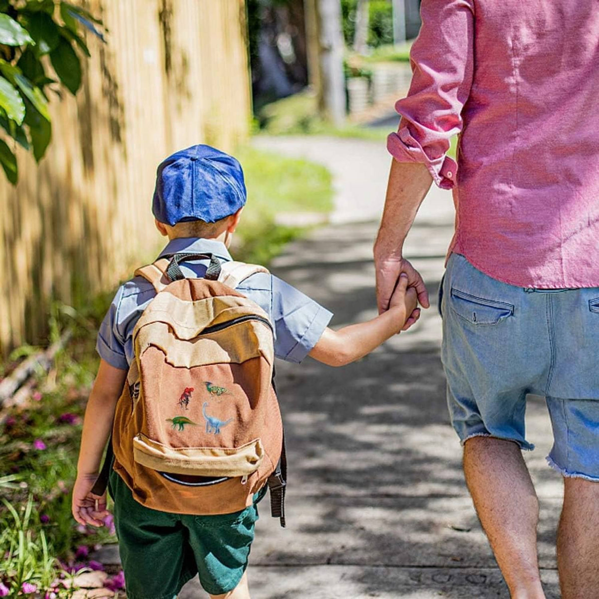 Child holding a small dinosaur figure while walking with an adult outdoors