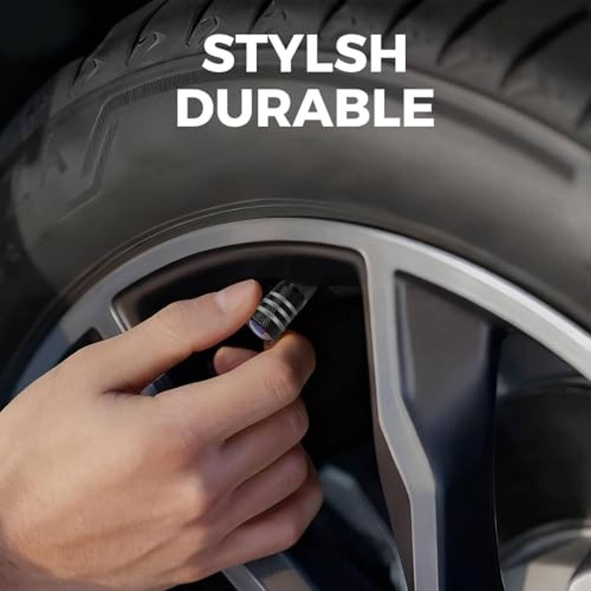 Hand tightening a black tire valve stem cap with U.S. flag emblem on a car wheel valve.