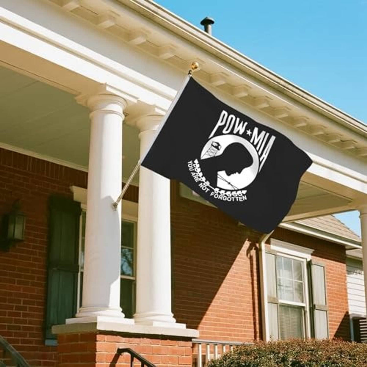 Black POW-MIA memorial flag on a pole outdoors, with white emblem and You Are Not Forgotten text