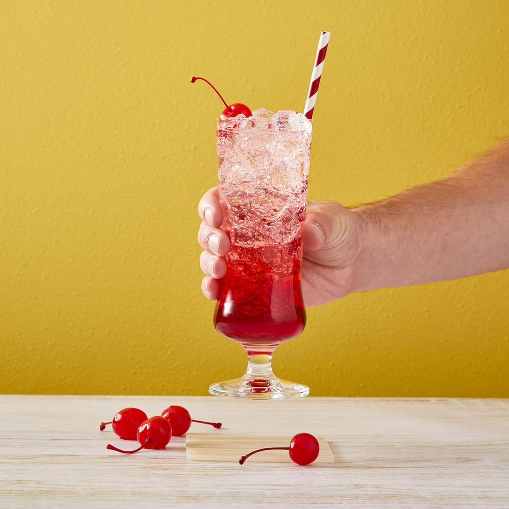 Hand holding a tall glass of cherry syrup drink with striped straw
