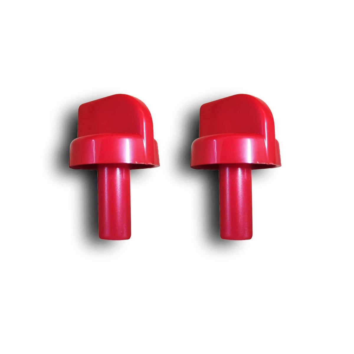 Two red plastic control valve knobs side by side, domed caps and stems