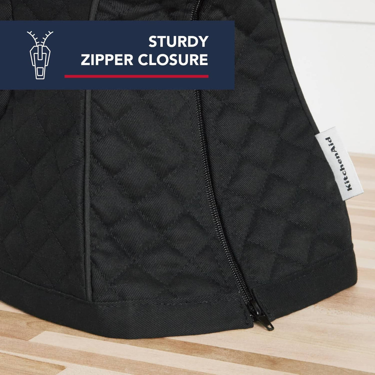 Black quilted stand mixer cover with visible zipper and side label