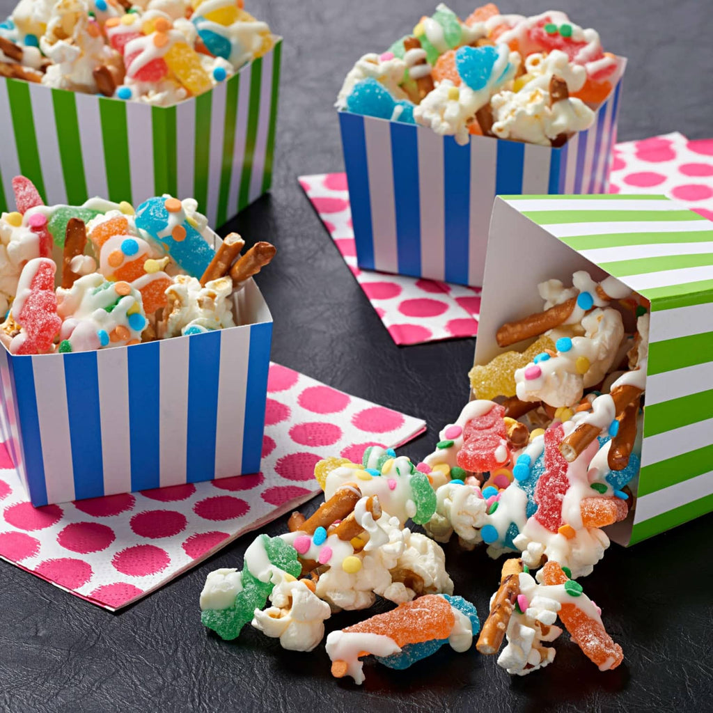 Colorful gummy candies scattered in striped popcorn cups and snack boxes