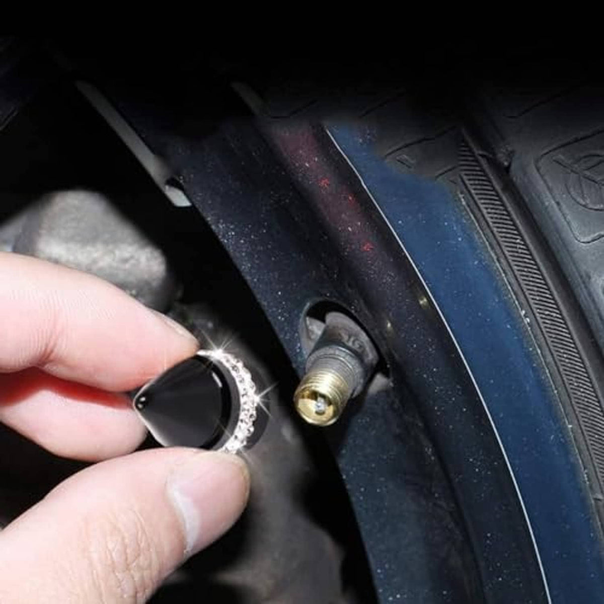 Black cone tire valve cap with silver rhinestone band held near the tire valve stem