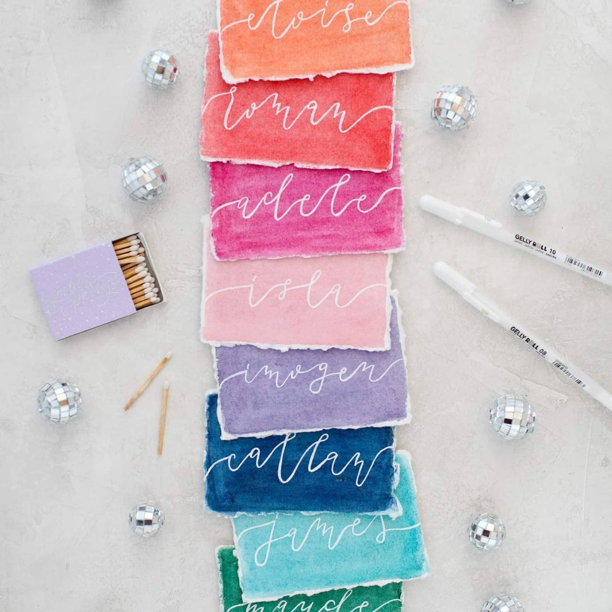 White ink gel pens with opaque writing on colorful paper swatches.