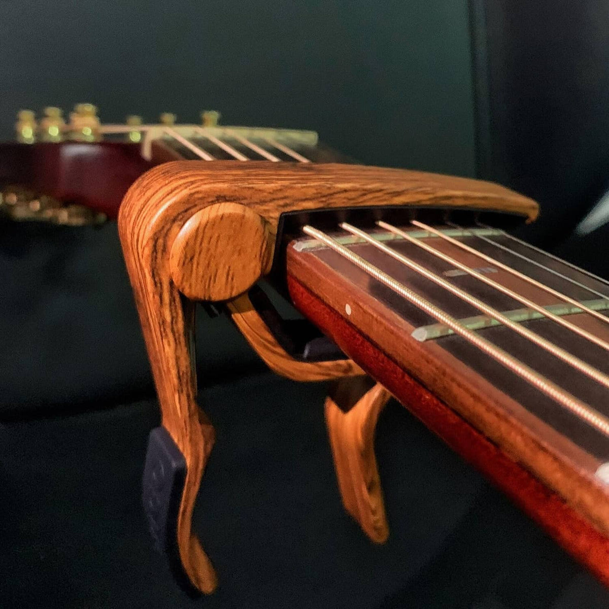 Rosewood woodgrain guitar capo clipped on guitar neck near frets