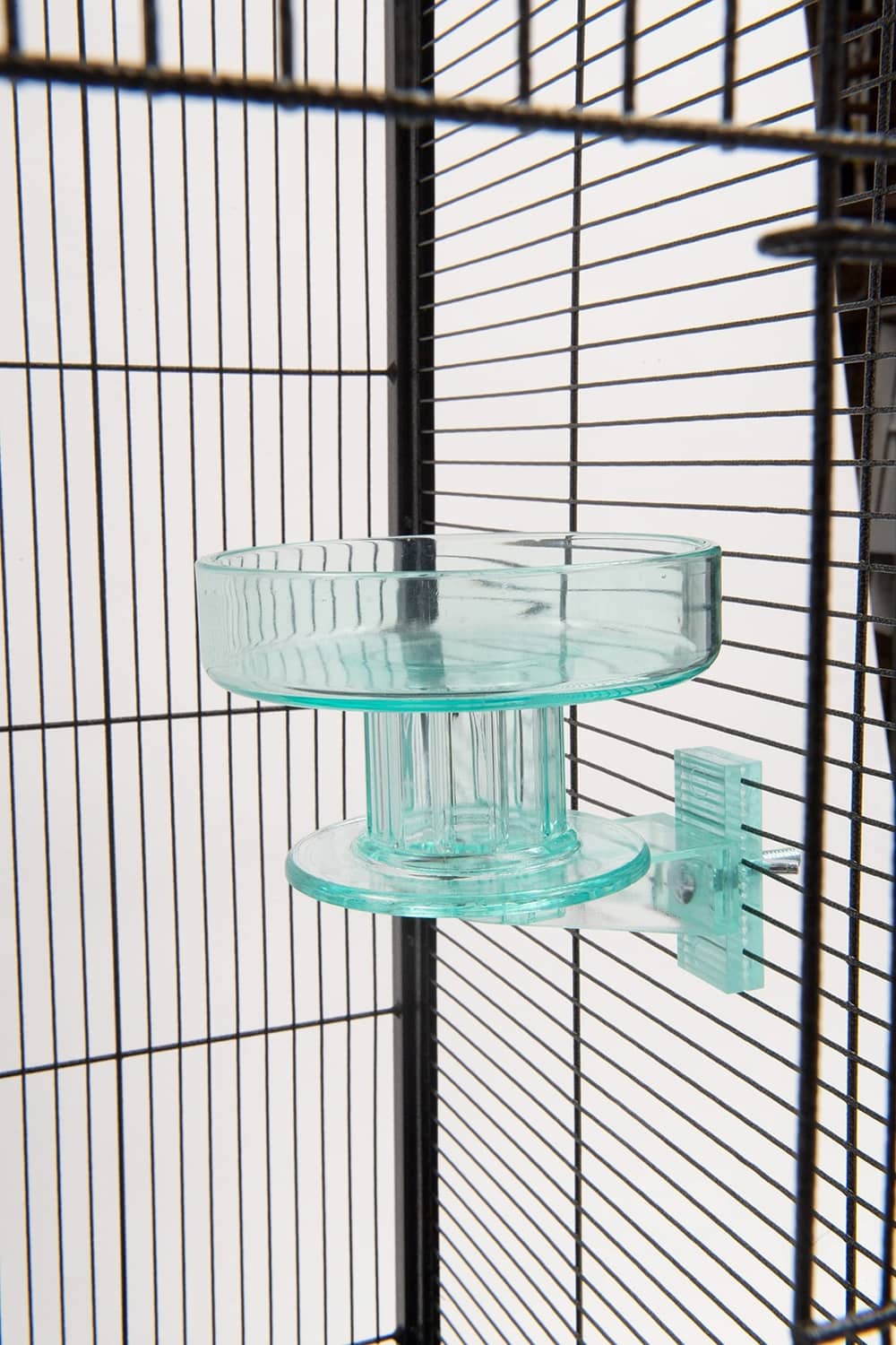 Turquoise bird bath bowl with pedestal mount inside a wire cage