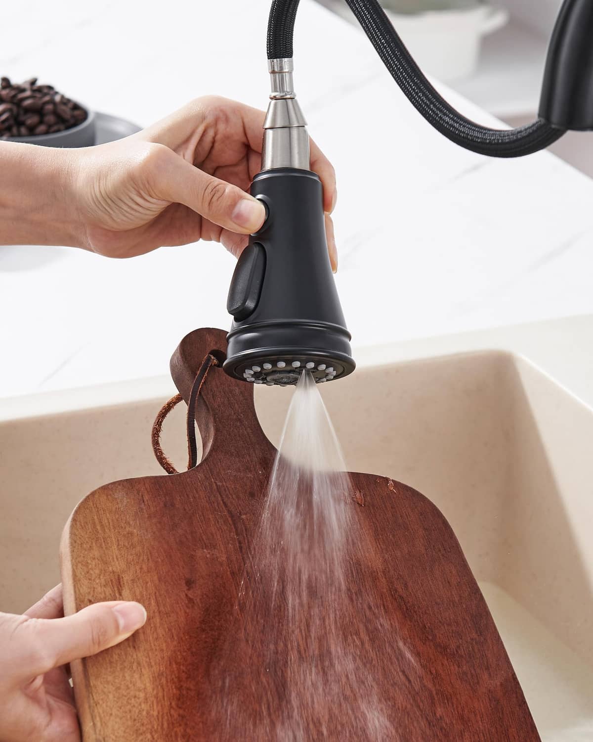 Matte black pull-down spray head rinsing a wooden cutting board