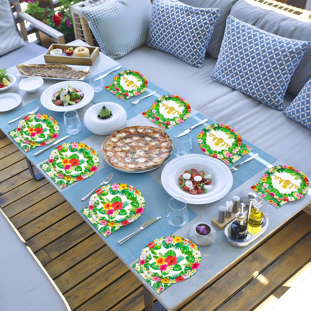 Tropical paper plates and napkins on outdoor picnic table, green foliage with 'aloha'