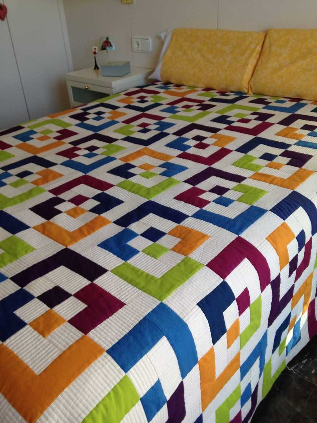 Bedspread quilt with multicolor geometric fabric blocks and navy trim