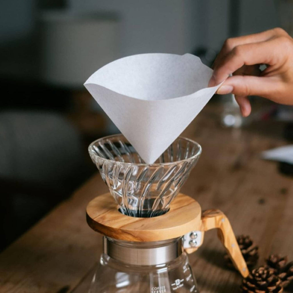 White cone paper coffee filter set on a dripper, held by hand