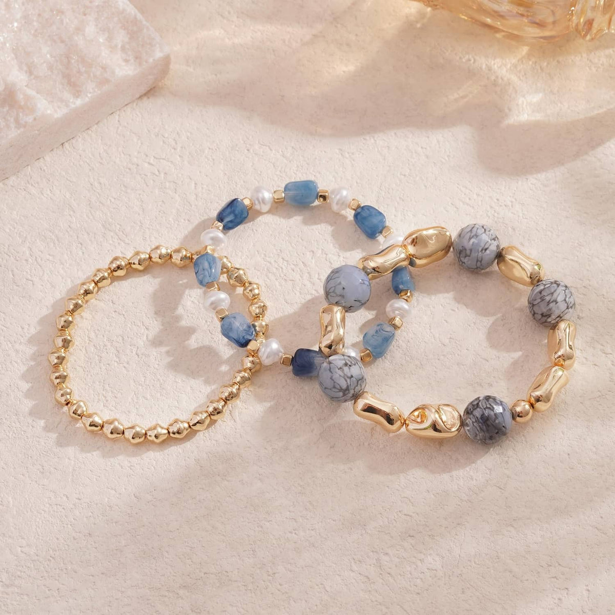 Stack of 3 blue and gray stone beaded stretch bracelets with gold clasp details
