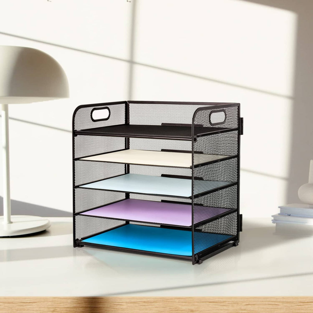 Black mesh 5-tier letter tray organizer with top handle, angled view on desktop.