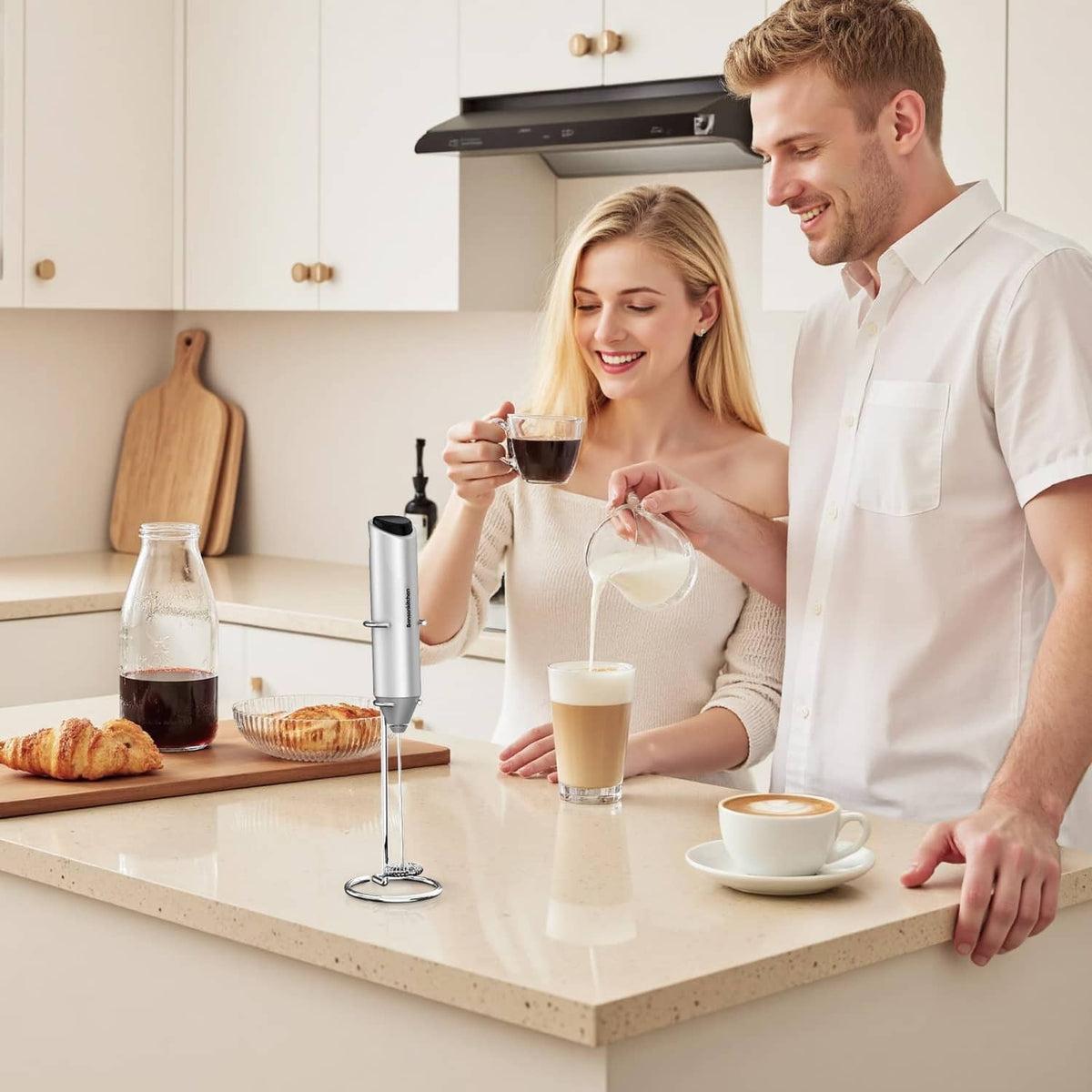 Silver milk frother on stand on countertop with glasses of frothed milk