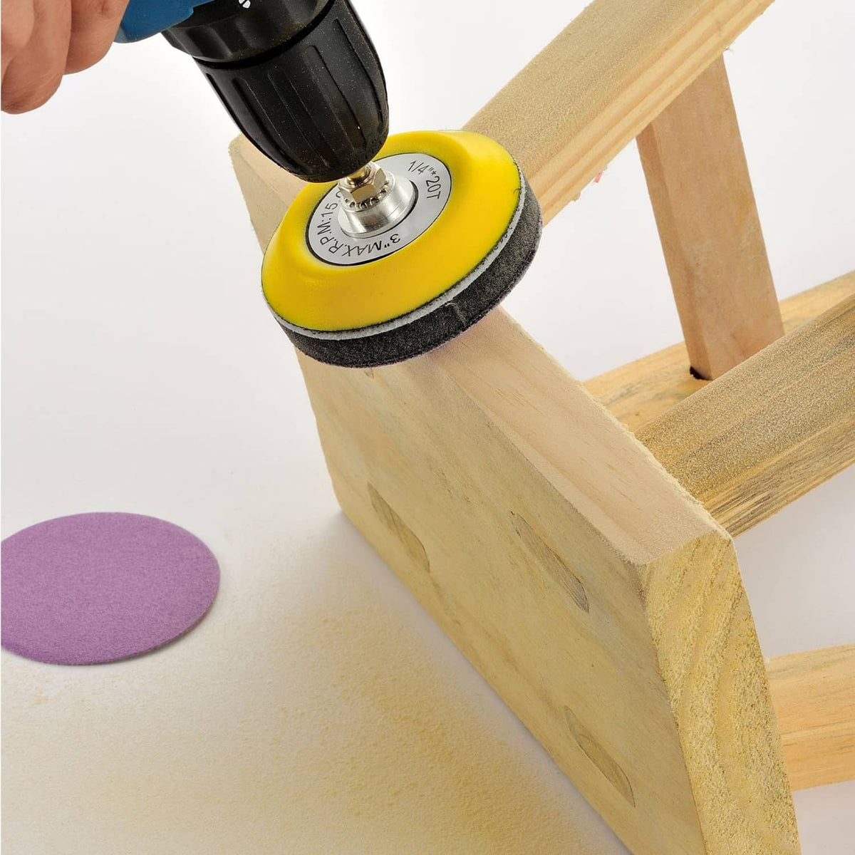 Purple sanding disc on a drill, sanding a wooden surface for smooth finishing