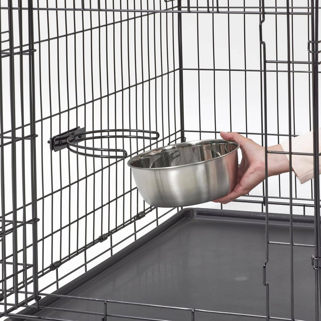 Hand holding a stainless steel bowl inside a black wire dog crate