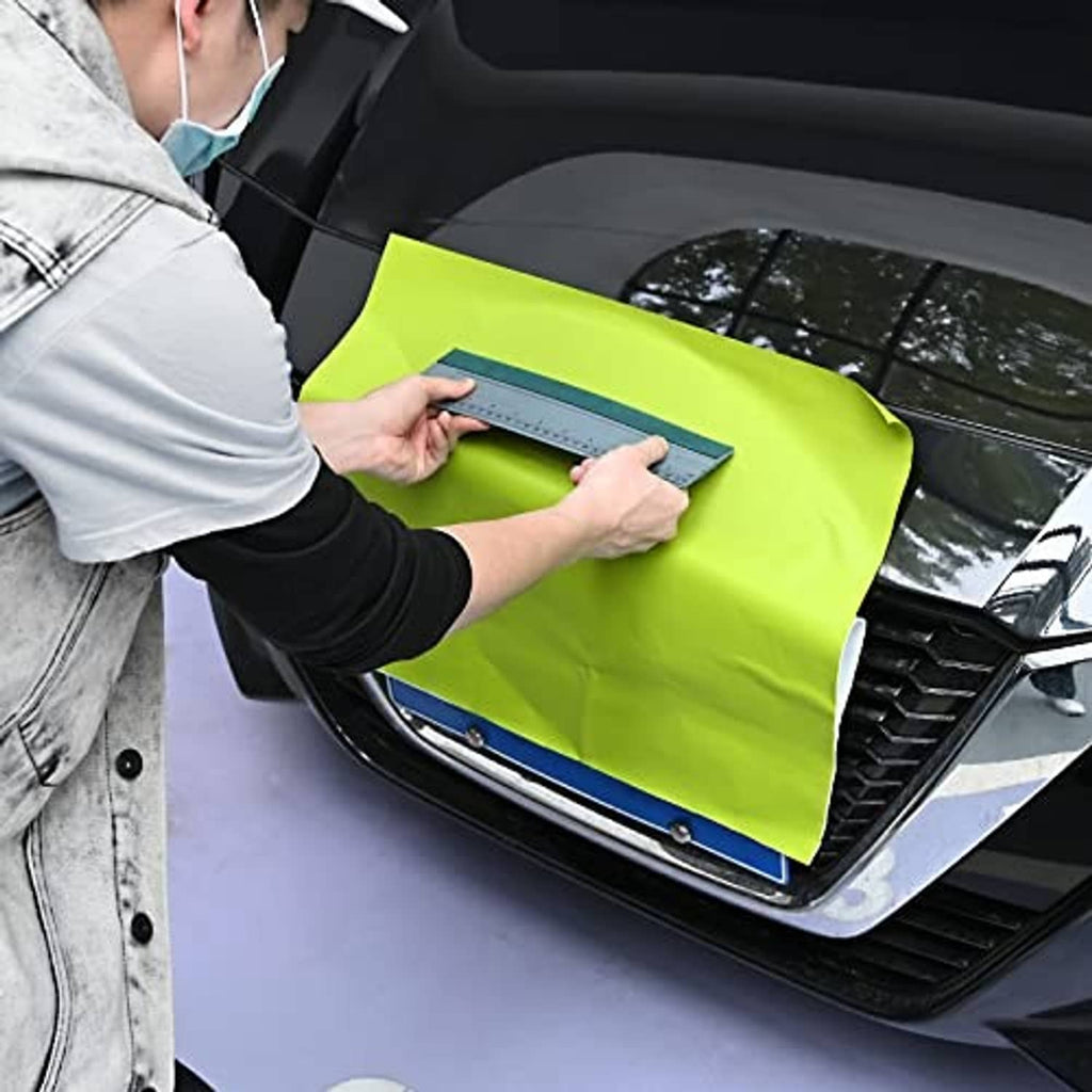 Vinyl wrap squeegee with clear ruler and felt edge, held near a car window.