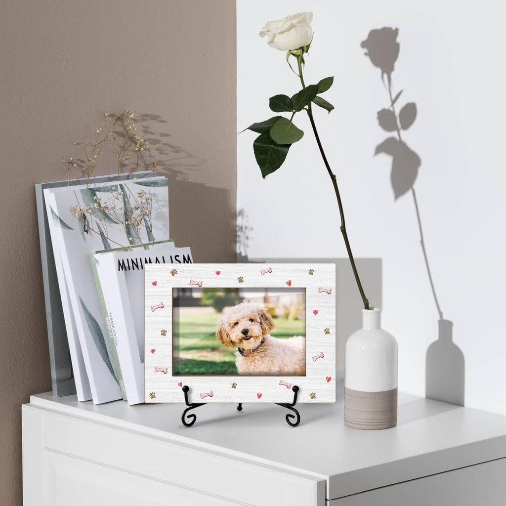 White dog photo frame with paw and bone pattern on iron stand, on a shelf.